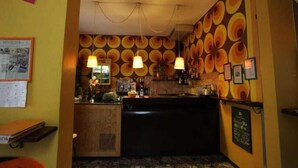 Zona de bar con mostrador, lámparas colgantes y una pared con diseños circulares.