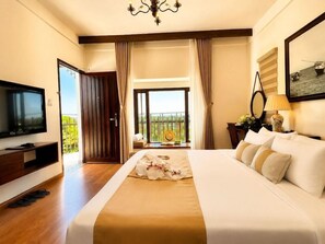Ein Hotelzimmer mit einem großen Bett, einem Fernseher, einem Balkon mit Blick und einem Kronleuchter.