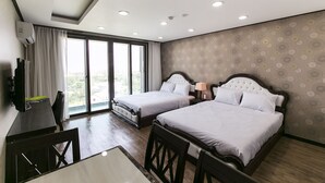 Een hotelkamer met twee bedden, een bureau met stoel, een televisie en grote ramen met gordijnen.