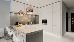 A modern kitchen with a central island, stainless steel appliances, and pendant lighting. - Exclusive Apartments (Kraków)