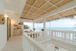 A beachside balcony with a thatched roof, white railings, and a view of the ocean. - Stories Stay Pool Villa Khao-tao Huahin (Tambon Nong Kae)