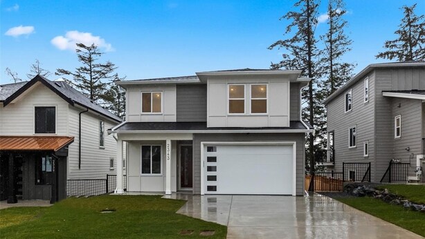 A two-story house with a garage, a front lawn, and tall trees in the background. - Luxury 2-Bedroom Suite at Bear Mountain | Victoria (Langford)