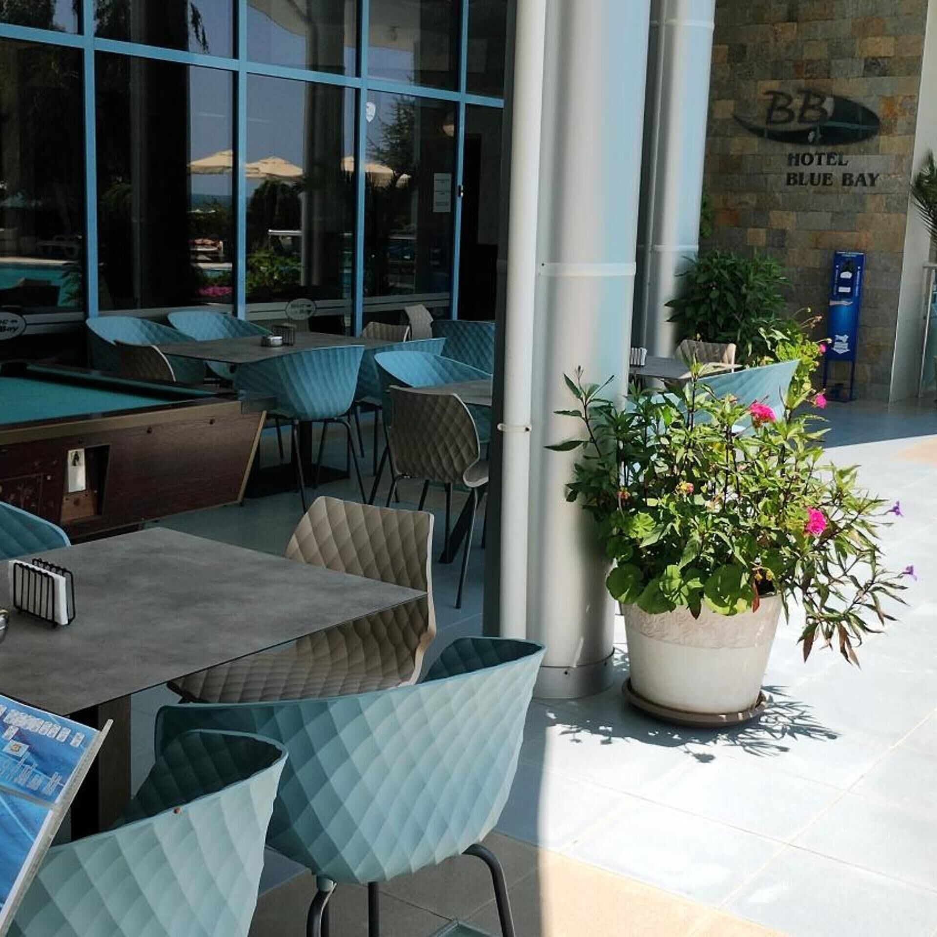 A pool table, chairs, and a potted plant outside a hotel.