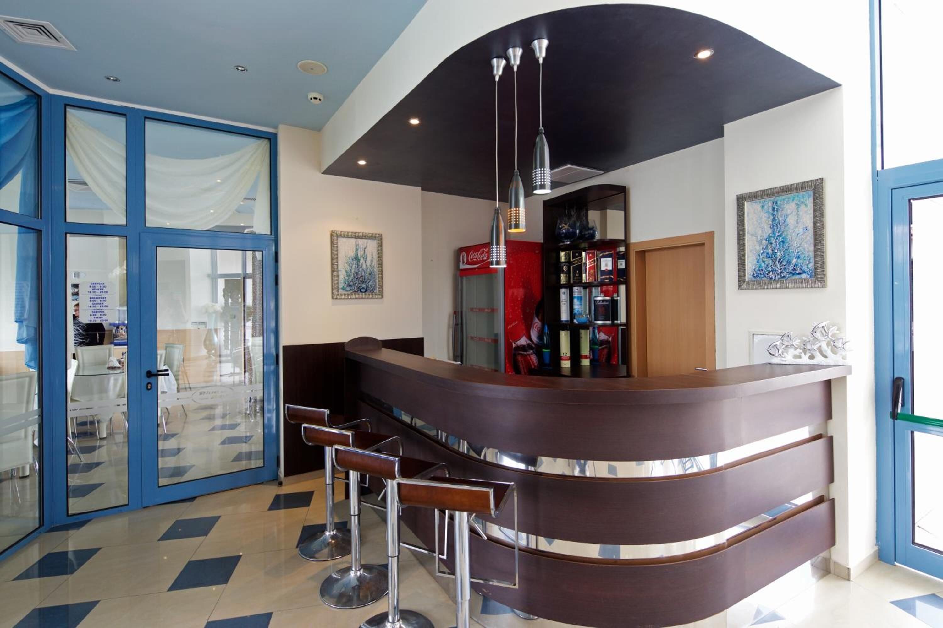 A modern bar area with a curved counter, bar stools, and a Coca-Cola refrigerator.