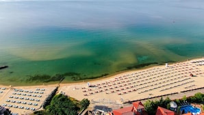 A beach with rows of sun loungers and a swimming pool. - Blue Bay Hotel (Nessebar)