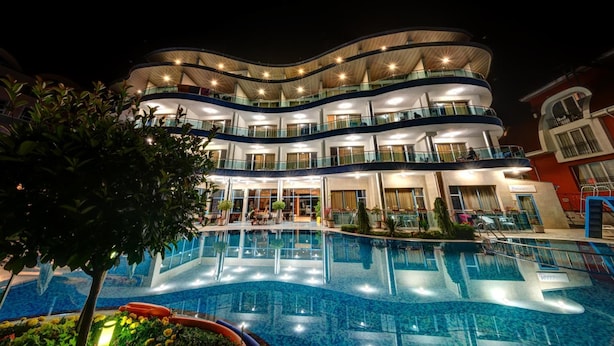 A multi-story hotel with a swimming pool, balconies, and indoor lighting. - Blue Bay Hotel (Nessebar)