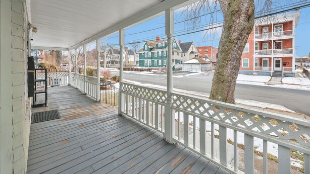 A covered porch with a white railing, overlooking a street with multi-story buildings and a tree. - Cozy 1-bedroom apartment in gorgeous Hartford with AC (Hartford)