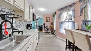 A kitchen with a sink, cabinets, and a dining area with chairs and a table. - Cozy 1-bedroom apartment in gorgeous Hartford with AC (Hartford)