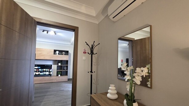 A hallway with a wooden reception desk, a mirror, and a coat rack. - Cosy Ground FL APT - Msida Marina Area (Msida)