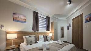 A hotel room with a large bed, two bedside tables, a headboard, and artwork on the walls. - Cosy Ground FL APT - Msida Marina Area (Msida)