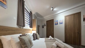 A hotel room with two beds, a wooden headboard, a large mirror, and a window with curtains. - Cosy Ground FL APT - Msida Marina Area (Msida)
