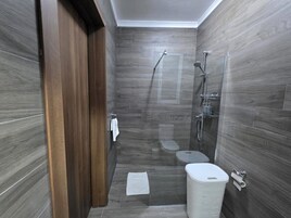 Un baño moderno con ducha, inodoro y perchero para toallas.