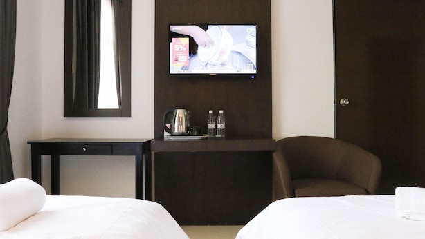 A hotel room with two beds, a TV mounted on the wall, a small table with a coffee maker and water bottles, and a chair. - The Payang Scout Hotel (Kuala Terengganu)