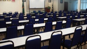 A conference room with rows of blue chairs and white tables, a whiteboard, and a podium. - The Payang Scout Hotel (Kuala Terengganu)