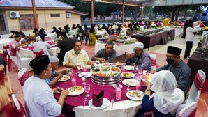 A group of people dining at a covered outdoor event with tables set with various dishes and drinks. - The Payang Scout Hotel (Kuala Terengganu)