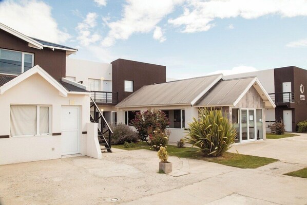 A modern hotel with a flat roof, a covered outdoor area, and a small garden. - Amigo del Mundo Hosteria y Apart Hotel (El Calafate)