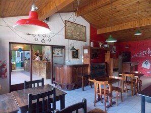 En restauranginteriör med träbord och stolar, en röd och vit hänglampa och en röd vägg med en väggmålning som föreställer ett musiknot.