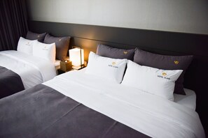 A hotel room with two beds, each with white linens and pillows branded with 'HOTEL B.cent'. There is a bedside table with a lamp and a tissue box. - B Cent Hotel (Busan)