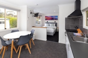 Une chambre d’hôtel compacte comprenant un coin repas, un lit avec vue et une kitchenette.