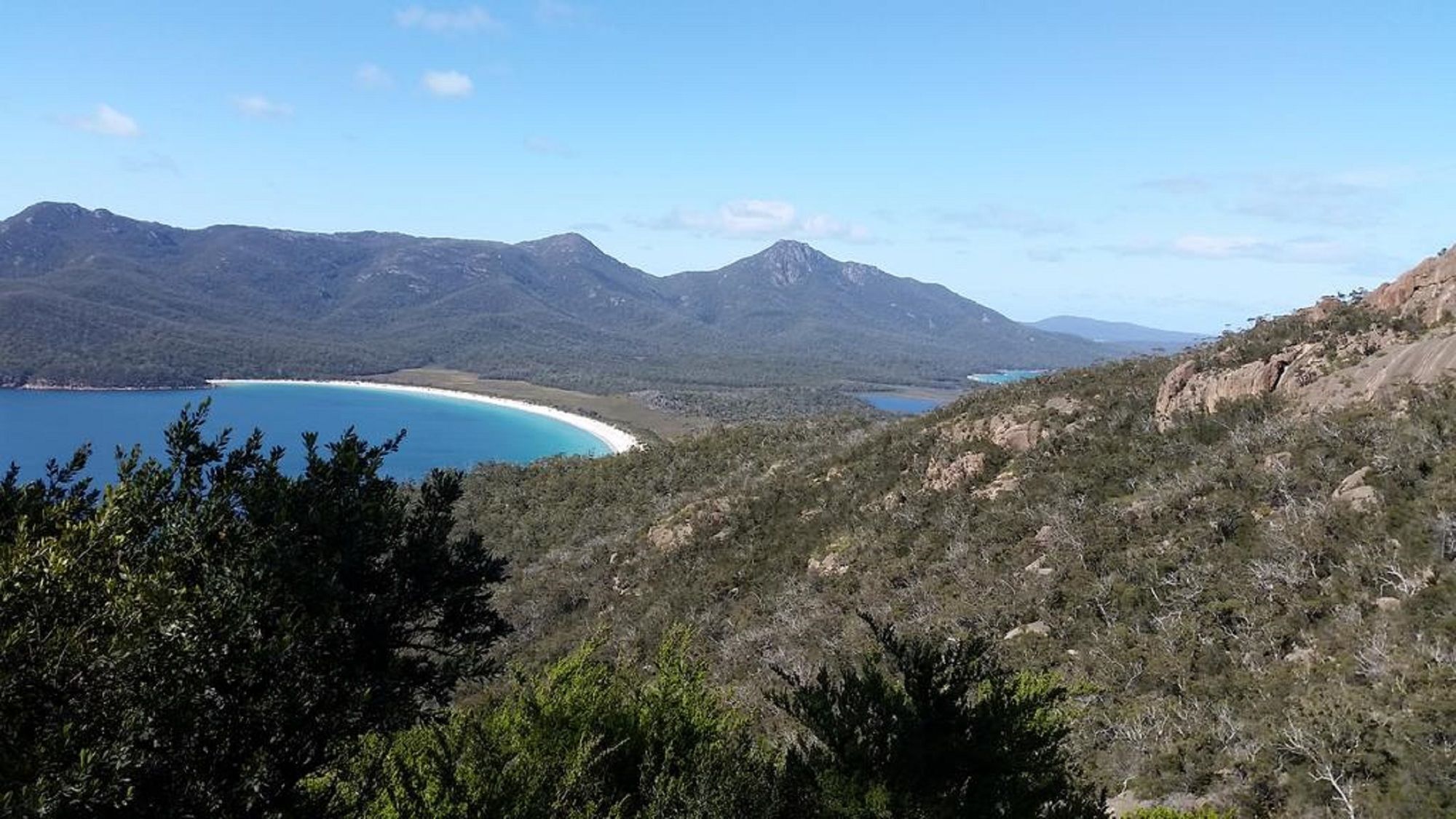 Un paysage montagneux avec un lac aux eaux d’un bleu profond et une plage.