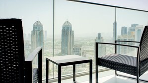 Une chambre située dans un immeuble de grande hauteur, offrant une vue panoramique sur la ville, et comprenant deux fauteuils et une petite table.