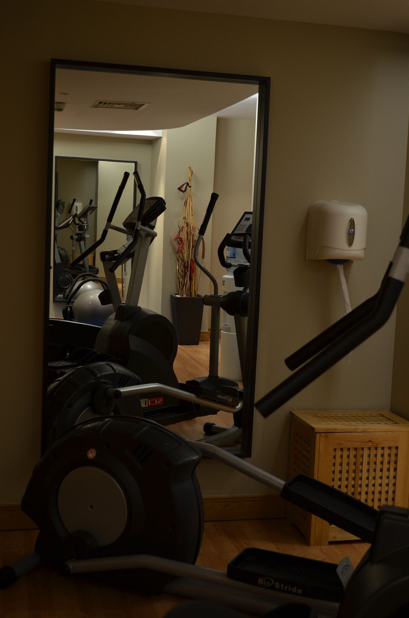 Un gimnasio en casa con equipo de ejercicio, un espejo y un taburete de madera.