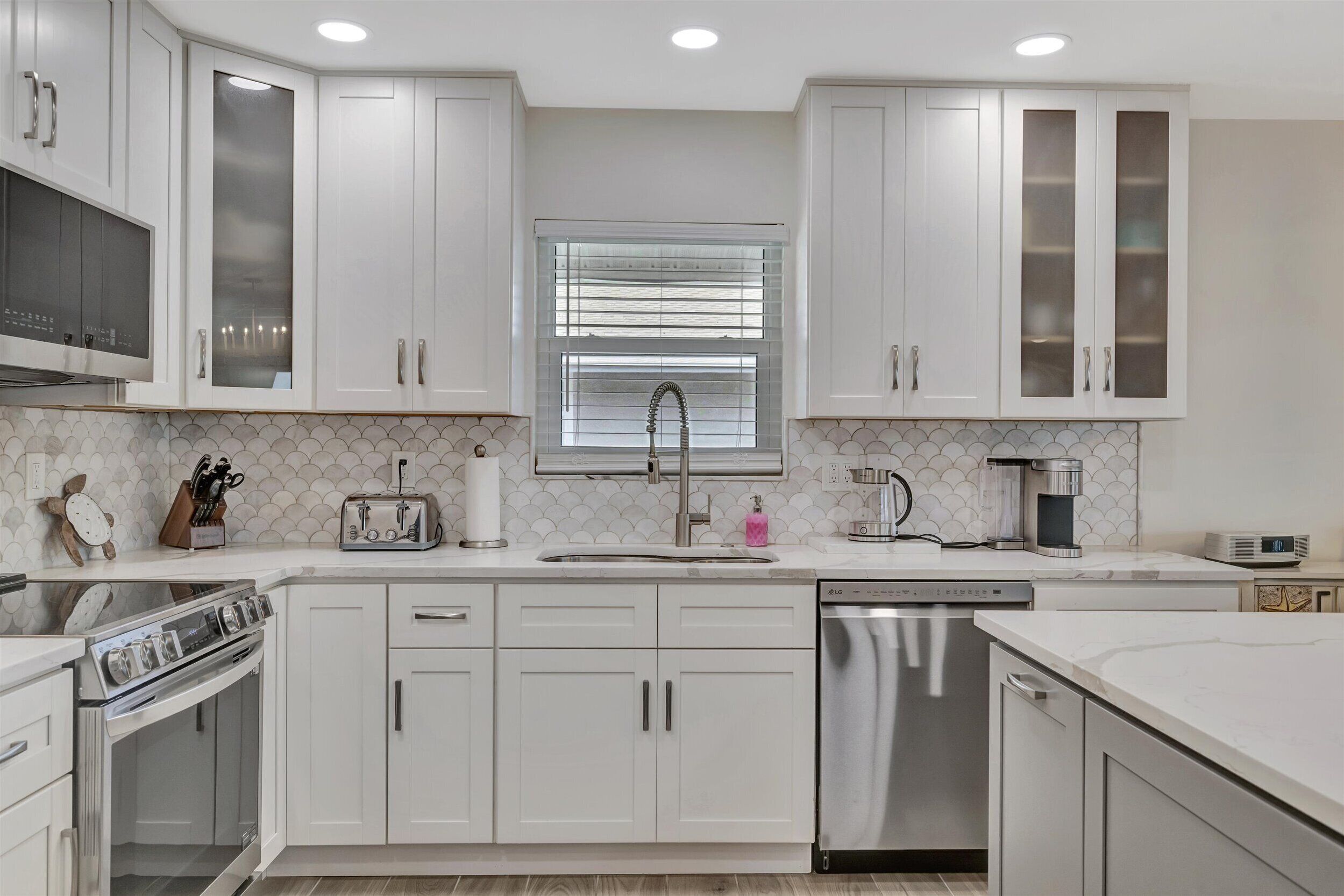 A modern kitchen with white cabinetry, a stainless steel dishwasher, and a built-in oven.