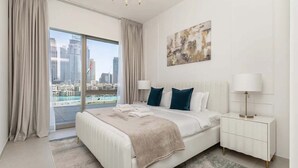 Moderni hotellihuone, jossa on suuri sänky, kaksi yöpöytävalaisinta, näkymä kaupunkiin ja panoraamakuva kaupunkimaisemasta ikkunasta.