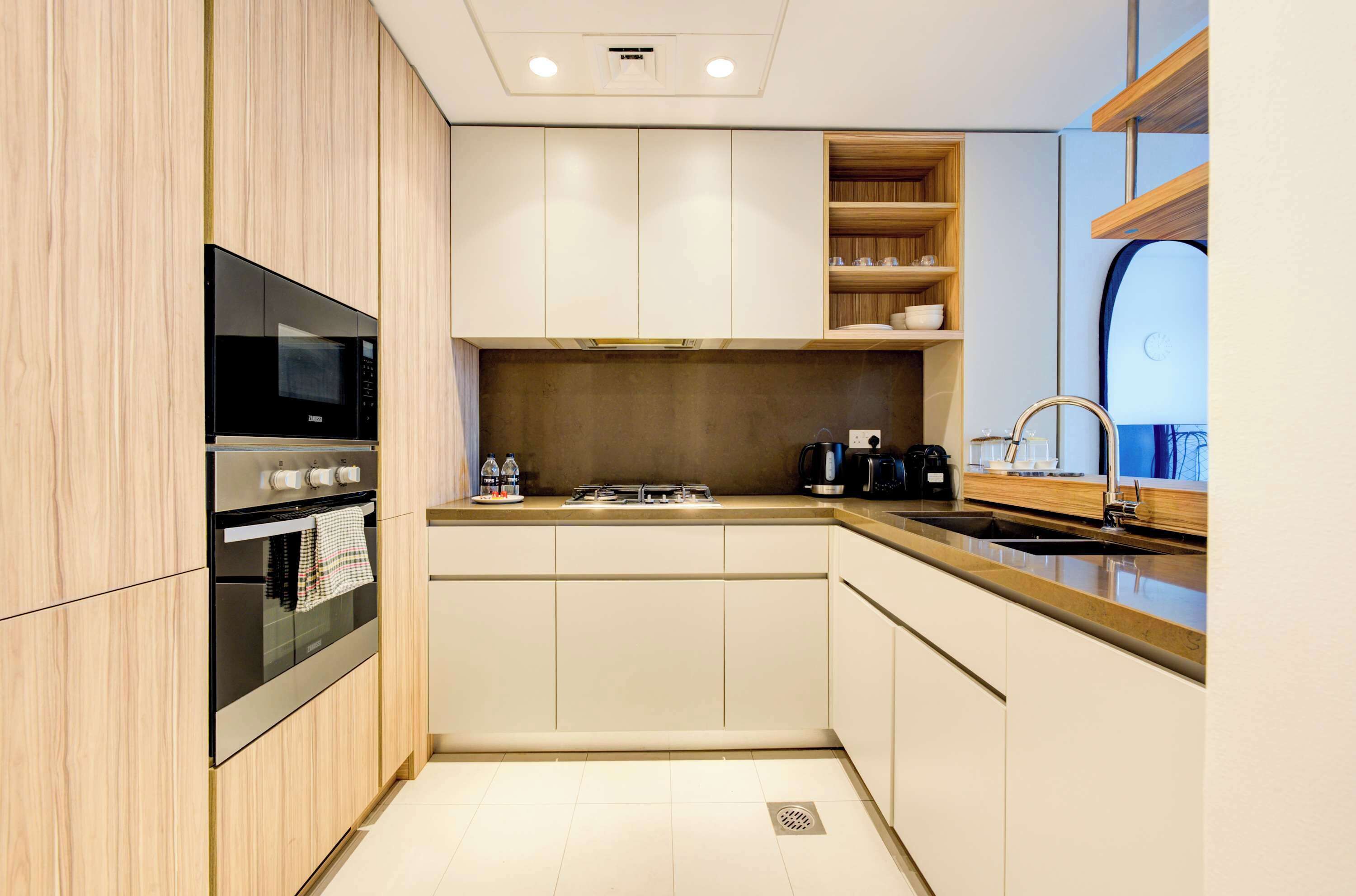 A modern kitchen with a built-in oven, microwave, and a coffee maker.