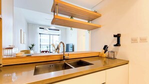 Una cocina moderna con un lavamanos doble, estantes de madera y vistas al salón.