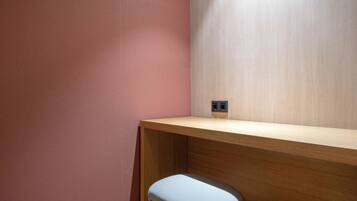A corner of a room with a wooden desk and a wall socket.