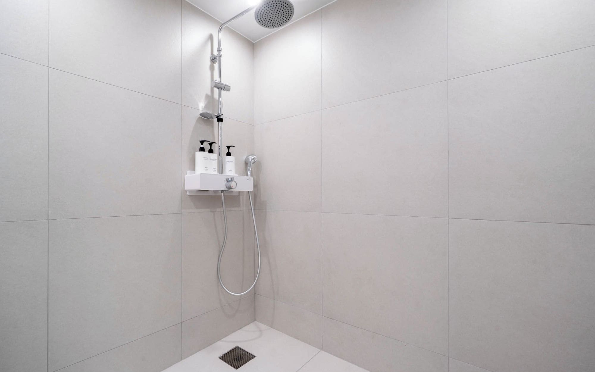 Una ducha moderna con cabezal de ducha de mano, panel de control en la pared y un accesorio de ducha manual.