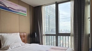 A hotel room with a large bed, a view of the city through floor-to-ceiling windows, and a painting on the wall. - Nomo Beijing Rd.jiedenga-mall Apartment (Guangzhou)