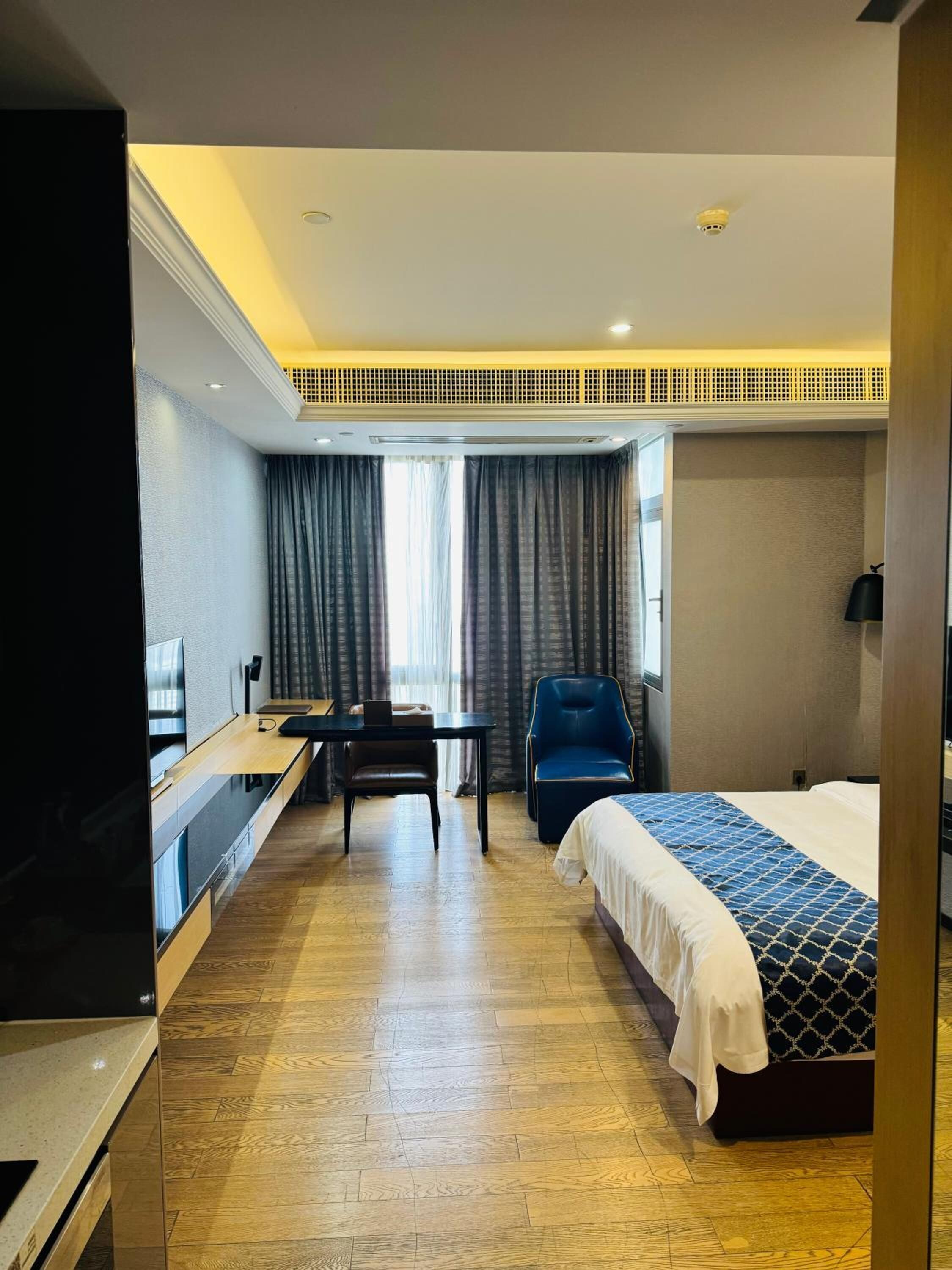 A hotel room with a bed, a desk, a chair, and a TV.