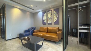 A modern living room with a leather sofa, a blue armchair, and a glass partition. - Nomo Beijing Rd.jiedenga-mall Apartment (Guangzhou)