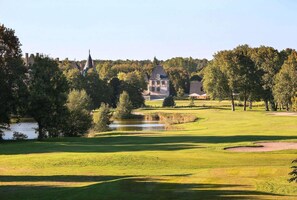 Golfkenttä, jossa on lampi, puita ja taustalla näkyvä rakennus.