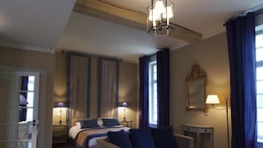 Un dormitorio con cama, mesitas de noche, escritorio, silla, lámpara, espejo y cortinas.