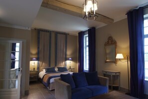 Une chambre à coucher comprenant un lit, des tables de chevet, un bureau, une chaise, une lampe, un miroir et des rideaux.
