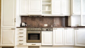 Een keuken met witte kasten, een roestvrijstalen oven en een granieten aanrecht.
