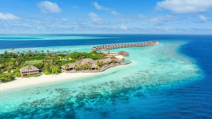 Ein überwasser-Resort mit Bungalow-Unterkünften, klarem türkisblauem Wasser und einer langen Pier, die sich ins Meer erstreckt.