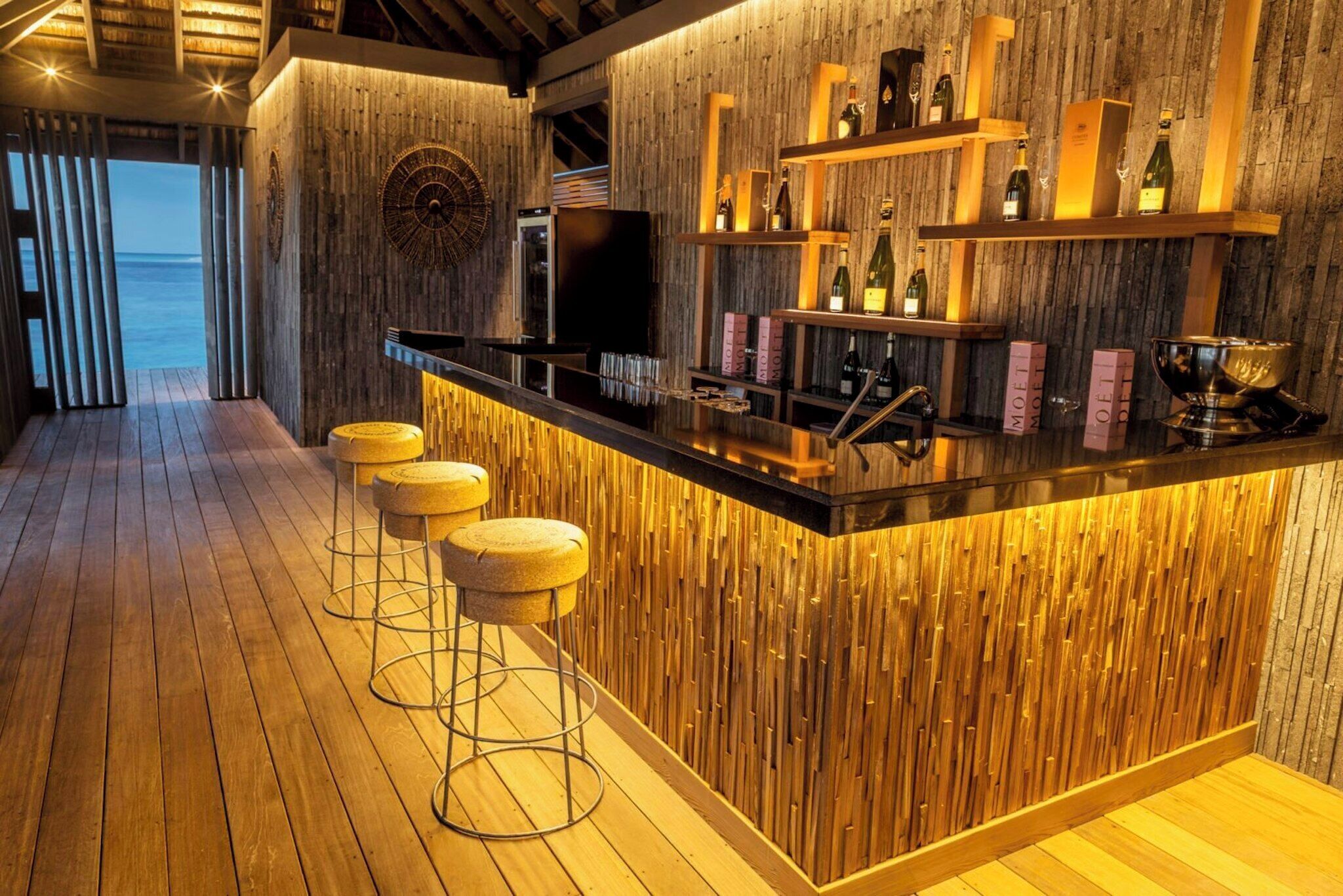 A bar area with wooden accents, a large mirror, and a view of the sea.