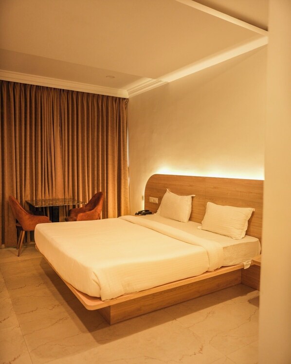 A hotel room with a large bed, a desk, and a chair.