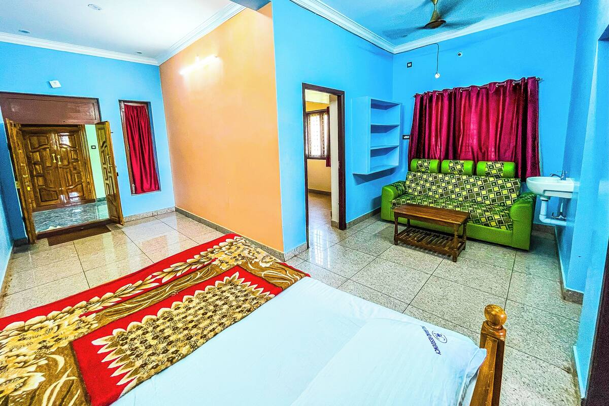 A room with a bed, a green sofa, a red curtain, and a ceiling fan.