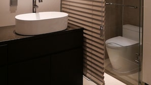 A modern bathroom with a round sink, a mirror, and a glass-enclosed shower. - Nesto Hongdae (Seoul)