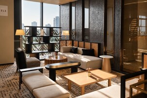 Un área de estar moderna con sofá, sillones, una mesa de centro y una estantería.