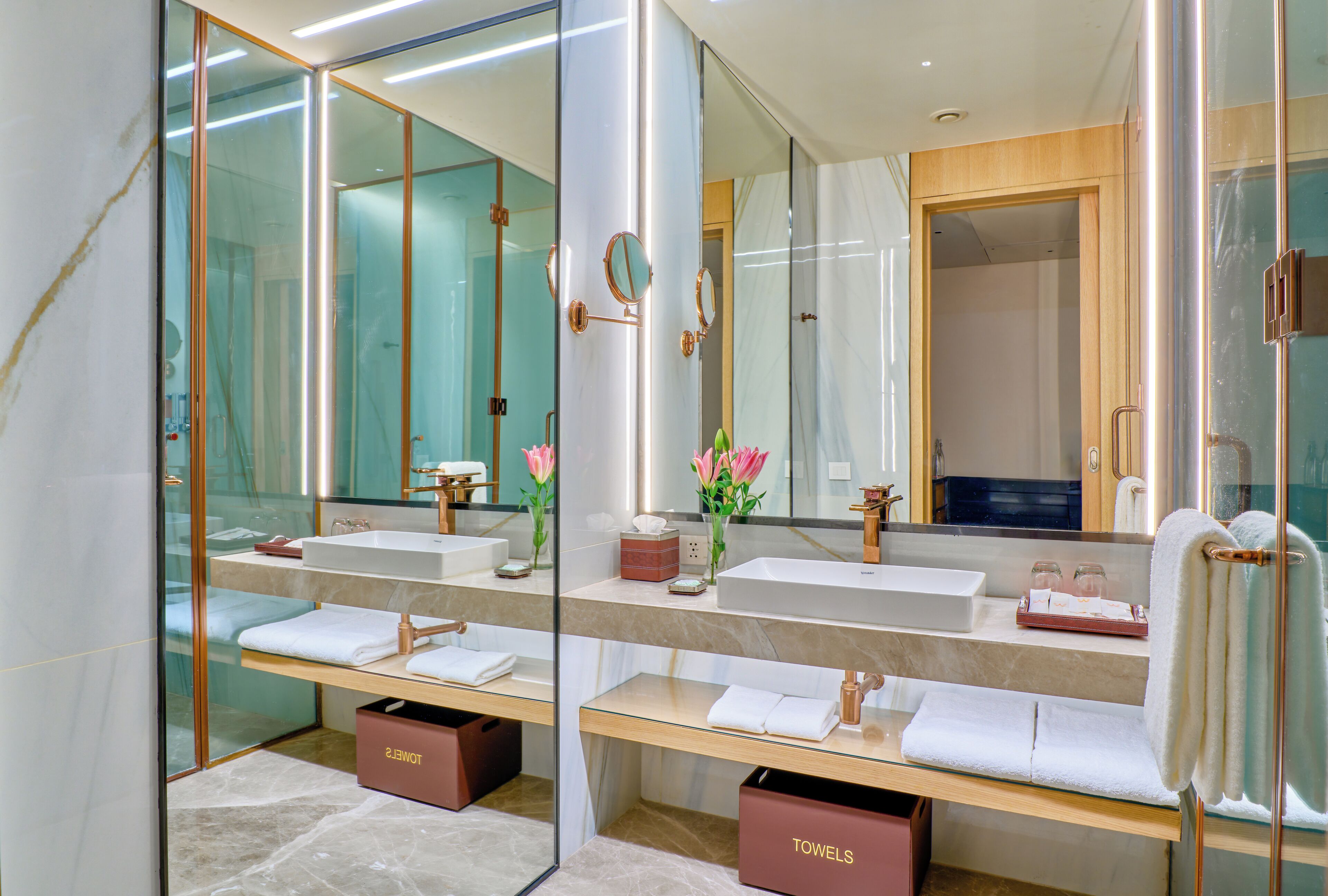 Ein modernes Badezimmer mit zwei Waschbecken, einem großen Spiegel und einer Duschkabine aus Glas.