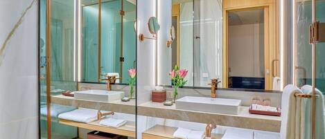 A modern bathroom with two sinks, a large mirror, and a glass shower enclosure.