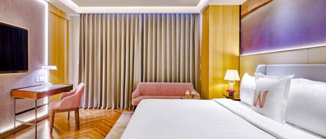 A hotel room with a large bed, a desk with a chair, a TV, and a curtain.