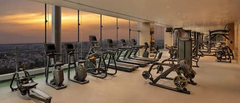 A gym with cardio equipment, weight machines, and a city view.