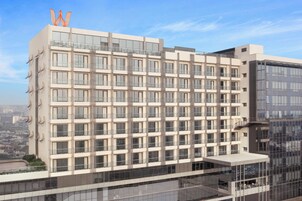 Un hotel moderno de varios pisos con fachada de diseño geométrico, ventanas amplias y balcones.